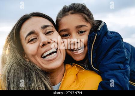 Felice madre latina e figlia bambina che si divertono in inverno all'aperto. Amore per la famiglia e vacanze in viaggio Foto Stock