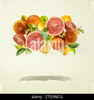 Gruppo di agrumi volanti con foglie verdi su sfondo giallo chiaro sopra l'ombra. Stile di vita sano. Levitazione del cibo. Telaio Foto Stock