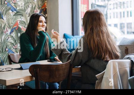 Disintossicazione digitale amici. Due amici si godono una conversazione faccia a faccia con un caffè in caffetteria, disintossicazione digitale impegnandosi in interazioni personali senza Foto Stock