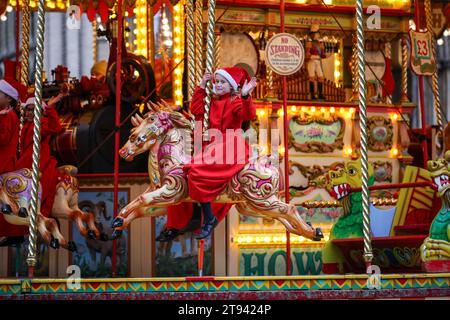 I coristi della Cattedrale di Ely fanno un giro sulla giostra tradizionale al mercatino di Natale della città dopo la pratica del coro mattutino . Foto Stock