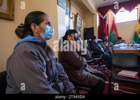 Viacha, la Paz, Bolivia – 16 agosto 2022: Donna boliviana con maschera siediti e ascolta in una sala riunioni con bandiere Foto Stock