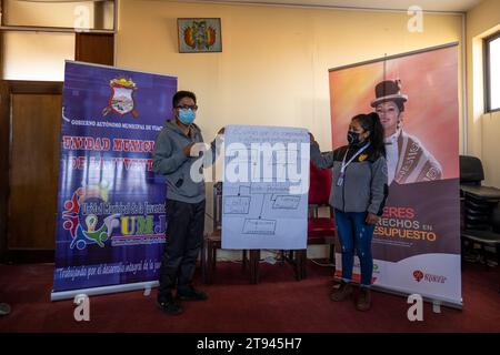 Viacha, la Paz, Bolivia – 16 agosto 2022: Una donna boliviana e un uomo con maschere parlano al pubblico in una sala riunioni Foto Stock