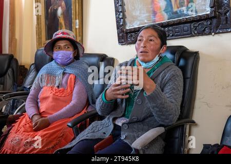 Viacha, la Paz, Bolivia – 16 agosto 2022: Due donne boliviane con maschere parlano al pubblico in una sala riunioni Foto Stock