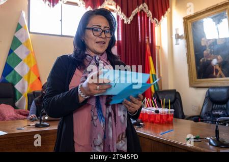 Viacha, la Paz, Bolivia – 16 agosto 2022: La donna boliviana parla in una sala riunioni di una bandiera Wiphala Foto Stock