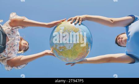 Una ragazza e un ragazzo girano un globo del mondo. Il concetto di pace e creazione. Foto Stock