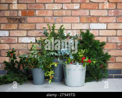 Secchi di fogliame natalizio foraggiato, tra cui rami holly, eucalipto e conifere sempreverdi, perfetti per creare corone o organizzare feste Foto Stock