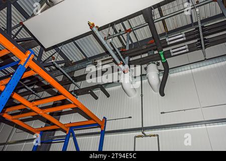 Un evaporatore e tubazioni vicino al soffitto nel congelatore di un magazzino di stoccaggio a freddo (refrigerazione industriale). Foto Stock