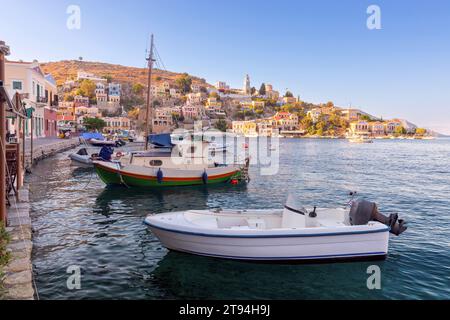 Case tradizionali colorate e barche da pesca nel villaggio greco di Symi sulla baia al tramonto. Grecia. Foto Stock