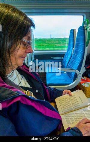 Una donna che legge un libro durante un viaggio in treno. Foto Stock
