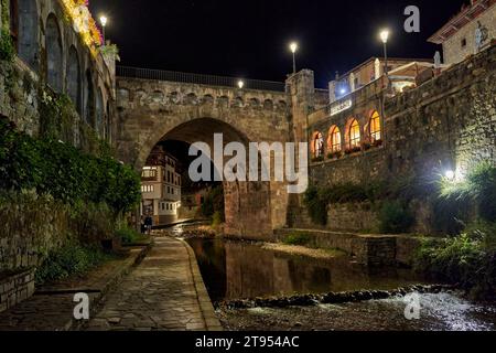 Potes, Cantabria, Spagna 08 02 2023: Città medievale di Potes di notte con ponte e fiume Deva lungo il suo percorso. Nella regione di Liebana, Cantabria, Spagna. Foto Stock