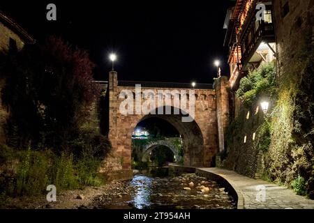 Città medievale di Potes di notte con il ponte e il fiume Deva lungo il suo percorso. Nella regione di Liebana, Cantabria, Spagna. Foto Stock