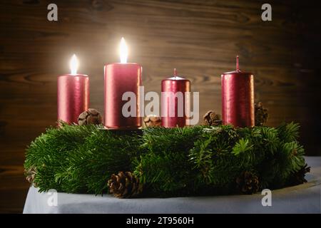 Per il secondo Avvento, due candele incendiate su una corona d'Avvento su uno sfondo di legno Foto Stock