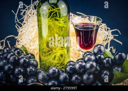 bicchiere da vino e bottiglia, uva nera e paglia Foto Stock