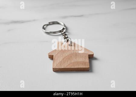 Portachiavi in legno a forma di casa su tavolo in marmo, primo piano Foto Stock