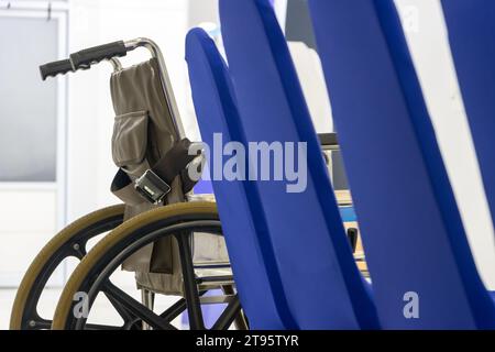 Una sedia a rotelle parcheggiata in fila accanto a sedie vuote Foto Stock