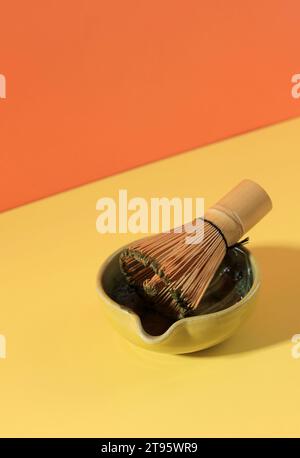 Tè Matcha e frusta di bambù su sfondo giallo e arancione Foto Stock