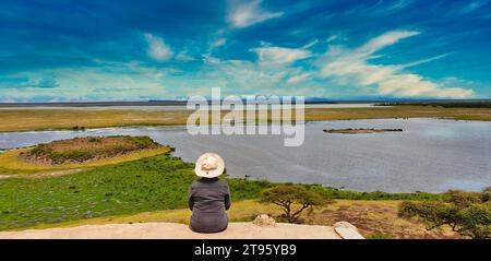 Amboseli, Kenya, 31-dicembre-2020 - Un turista contempla la vasta savana aperta del Parco Nazionale di Amboseli dalla cima della collina di osservazione Foto Stock