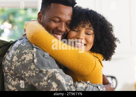 Felice soldato afroamericano che abbraccia la moglie a casa Foto Stock