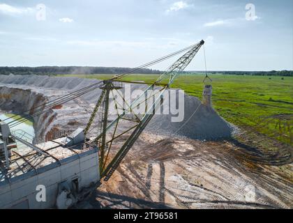 Il dragline a piedi con paranco e benna lavora in cava di pietra Foto Stock