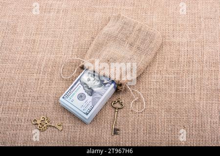 Chiave retrò e il pacchetto del dollaro USA in un sacco su una tela di canapa Foto Stock