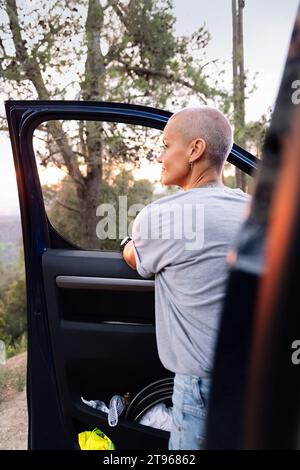 donna addossata al furgone che ammira il paesaggio Foto Stock