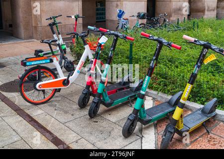MILANO, ITALIA - 4 AGOSTO 2021: Colorati scooter a noleggio e biciclette su un marciapiede nel centro di Milano Foto Stock