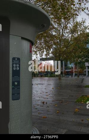 Parigi, Francia, 2023. Bagni pubblici Place de la Bastille, con l'Opéra Bastille e il suo enorme schermo sullo sfondo (verticale) Foto Stock