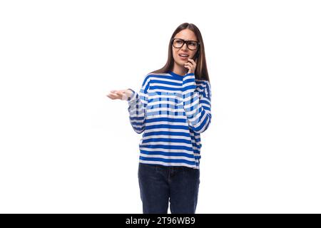 giovane donna snella con i capelli dritti indossa gli occhiali e parla al telefono Foto Stock