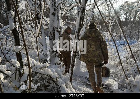 Kupyansk, Oblast' di Charkiv, Ucraina. 22 novembre 2023. I membri del servizio ucraino camminano tra gli alberi innevati dopo una missione antincendio. Comandando una posizione di artiglieria nella regione, le truppe ucraine si preparano all'inverno e ai potenziali assalti russi. (Immagine di credito: © Madeleine Kelly/ZUMA Press Wire) SOLO USO EDITORIALE! Non per USO commerciale! Foto Stock