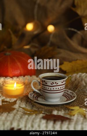 tazza di caffè sullo sfondo autunnale con foglie e candele Foto Stock