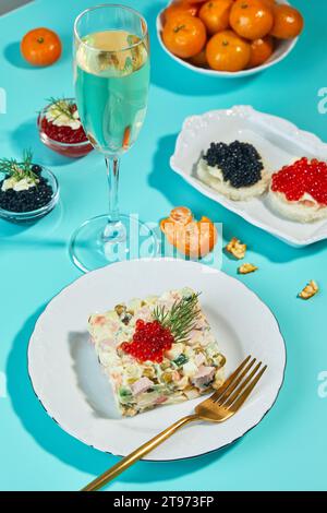 Tavolo di Capodanno o di Natale per feste in stile russo con champagne in vetro, mandarini e insalata Olivier in porzioni su piatto decorata con wi Foto Stock