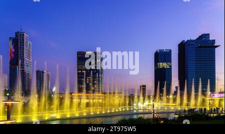 Uzbekistan, Tashkent - 29 settembre 2023: Una fontana con illuminazione laser e musica leggera nel Tashkent City Park di notte sullo sfondo Foto Stock