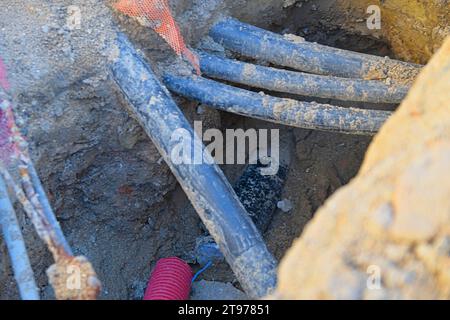 Cavi nella trincea. Cavi neri ad alta tensione nella trincea. Concetto di impianti elettrici, lavori di costruzione, ristrutturazione e costruzione di edifici Foto Stock