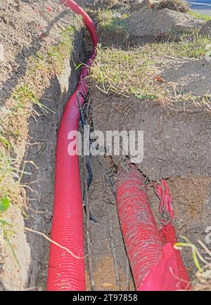 Cavi nella trincea. Cavi ad alta tensione nella copertura protettiva rossa nella trincea. Concetto di impianti elettrici, lavori di costruzione, Ren di costruzione Foto Stock