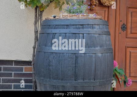 Vecchia botte di vino in legno con decorazioni rustiche. Vecchie pareti della cantina. Il concetto di vinificazione tradizionale e turismo moderno. Foto Stock
