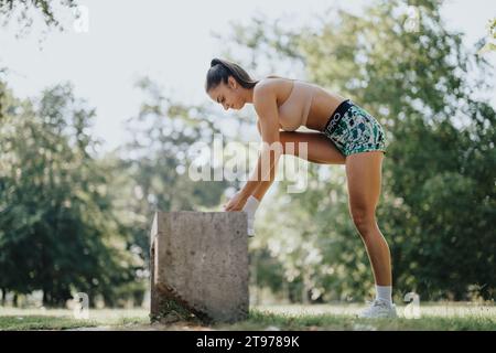 Gli amici si sfidano con il fitness all'aperto in un parco soleggiato, preparandosi per un allenamento con diversi sport, tra cui l'allenamento con la corda. Foto Stock