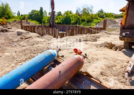 Apparecchiature di saldatura rosse e blu, serbatoi di ossigeno e azoto con valvole e manometri, bombole di gas acetilene posizionate su pali metallici all'interno della struttura Foto Stock