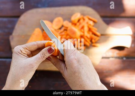 Donna che trita la carota su un tagliere di legno, primo piano su tavolo da  cucina bianco, vista dall'alto Foto stock - Alamy