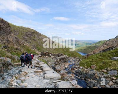 Vista posteriore di un gruppo di escursionisti con zaini che camminano lungo il Miners' Track dal Monte Snowdon, in uno splendido scenario delle montagne di Snowdonia in Galles, Regno Unito. Foto Stock