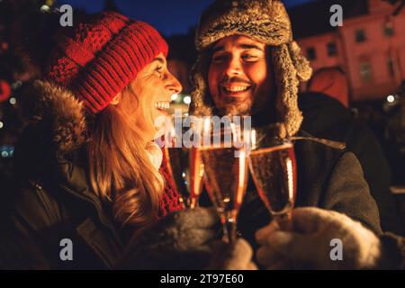 Coppia sorridente che si prende un bicchiere di champagne alla vigilia di Capodanno Foto Stock
