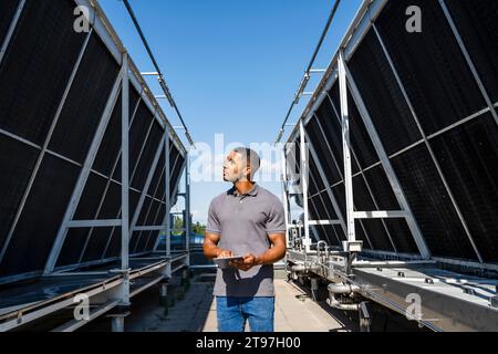 Dipendente con tablet digitale che controlla l'installazione della refrigerazione sul tetto Foto Stock