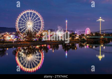 Germania, Baden-Wurttemberg, Stoccarda, Cannstatter Wasen, ruota panoramica luminosa che si riflette nel fiume Neckar di notte Foto Stock