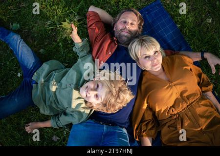 Genitori sorridenti che si rilassano con il figlio nel parco Foto Stock