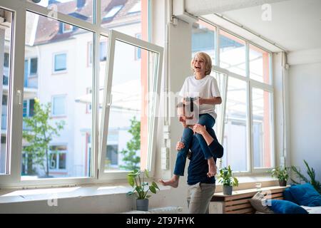 Felice padre che porta il figlio sulle spalle a casa Foto Stock