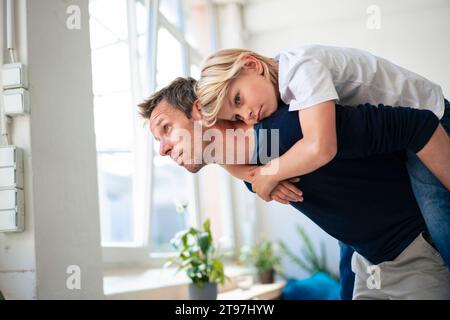 Padre che dà un passaggio da Piggyback a figlio a casa Foto Stock