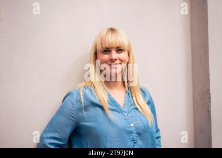 Donna sorridente in piedi davanti al muro Foto Stock