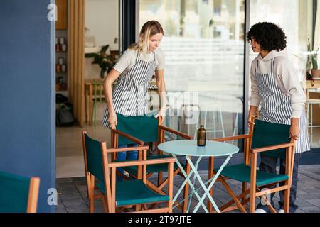 Baristi che sistemano sedie davanti al bicchiere al bar Foto Stock