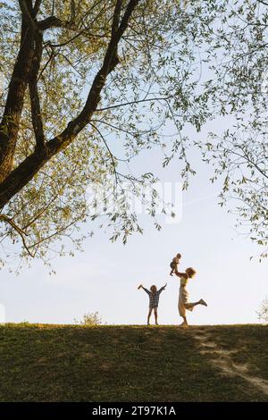 Madre felice che gioca con i bambini al parco Foto Stock
