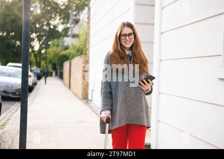 Giovane donna che cammina con il bastone sul marciapiede Foto Stock