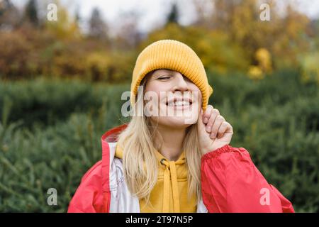 Donna sorridente che indossa un impermeabile e un cappello in maglia Foto Stock